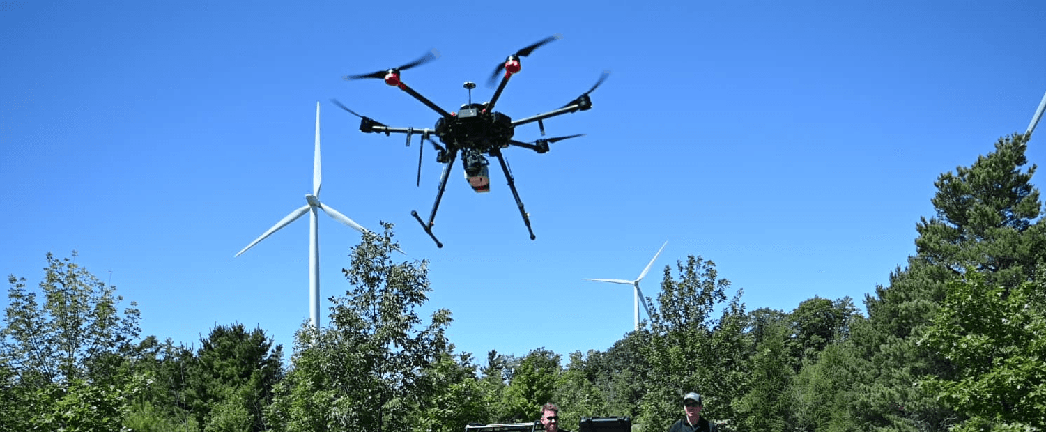 A winding road cuts through rocky terrain, surrounded by patches of green grass and illuminated by sunlight.