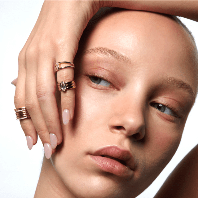 Model with hand over face wearing 3 gold rings Ground AI