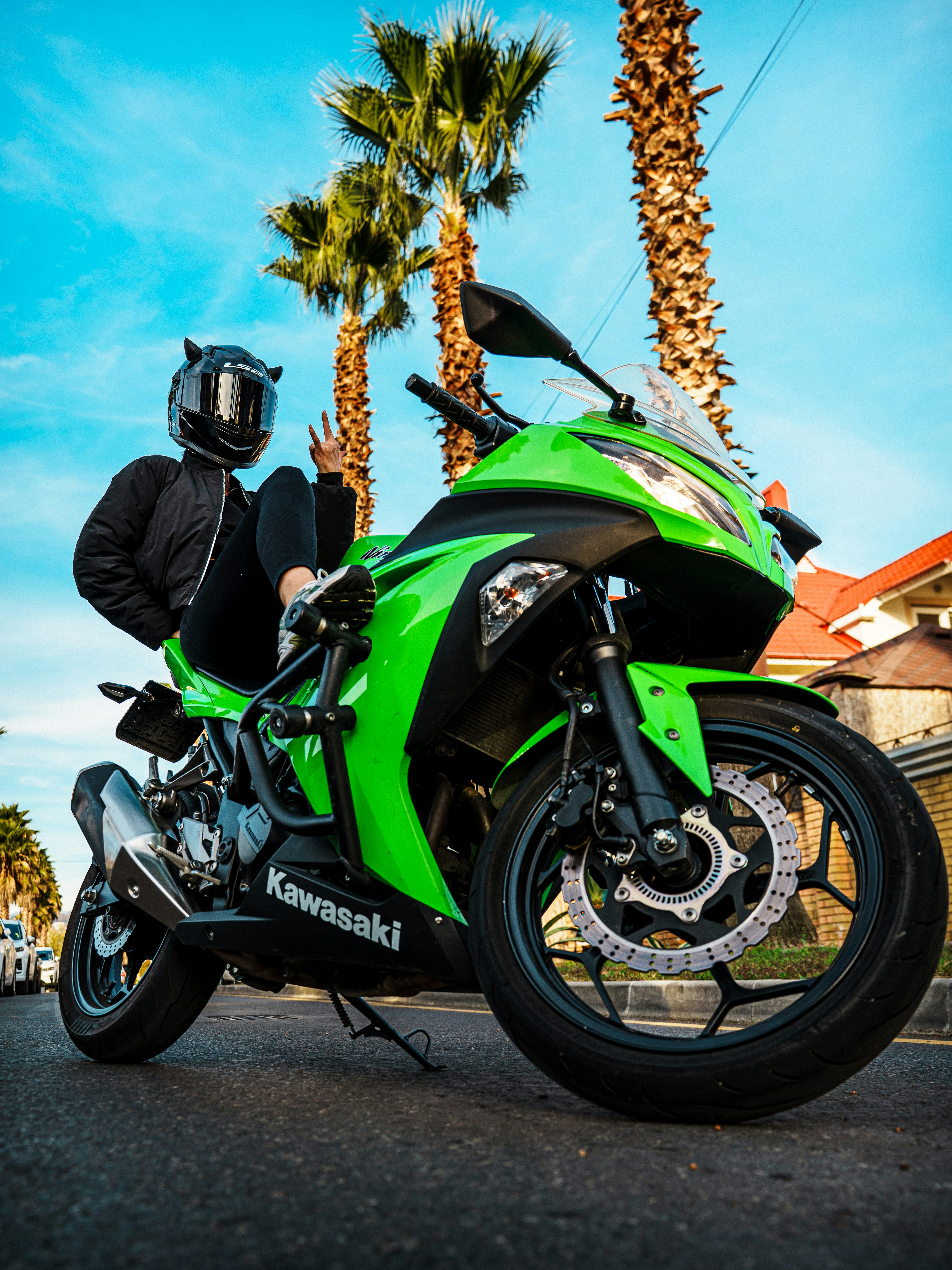 Person in helmet poses with a bright green kawasaki motorcycle.