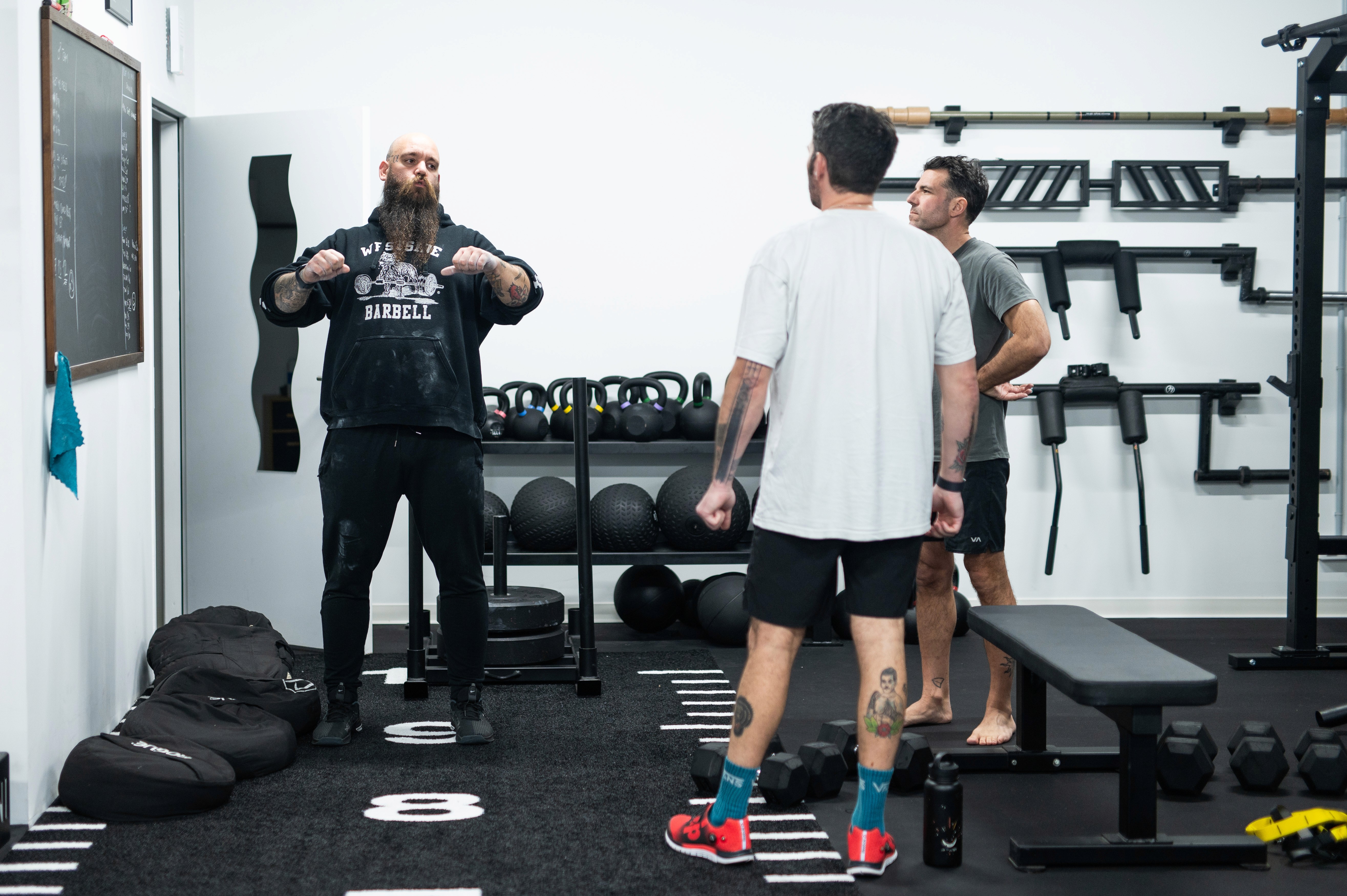 Two individuals are working out in a gym, focusing on dumbbells and strength training equipment.