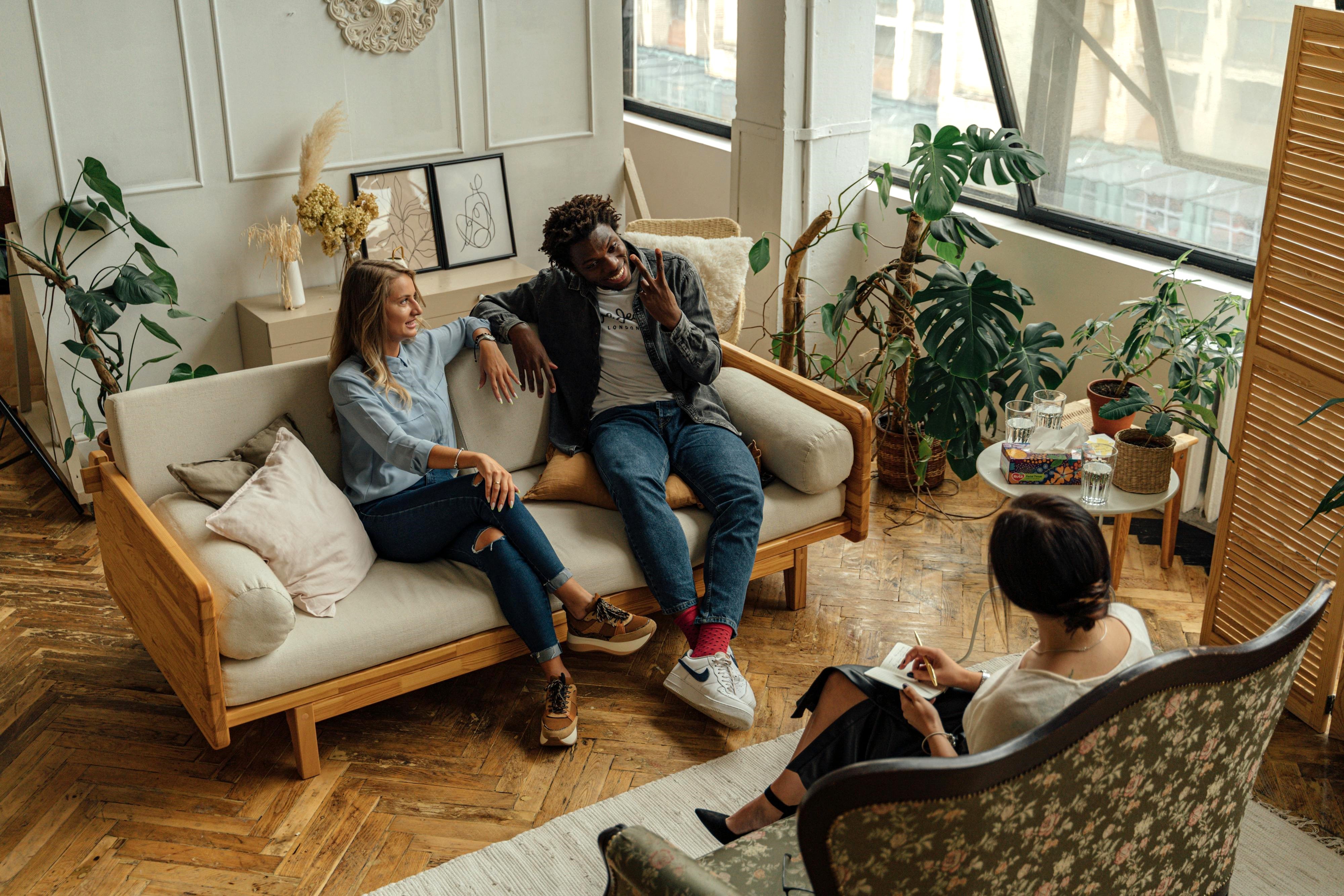 Couple sitting on a couch and talking with a therapist during a session in a cozy office.