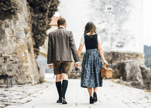 Bräutigam bindet der Braut im Dirndl erstmals die Schleife bei Hochzeit in Passau