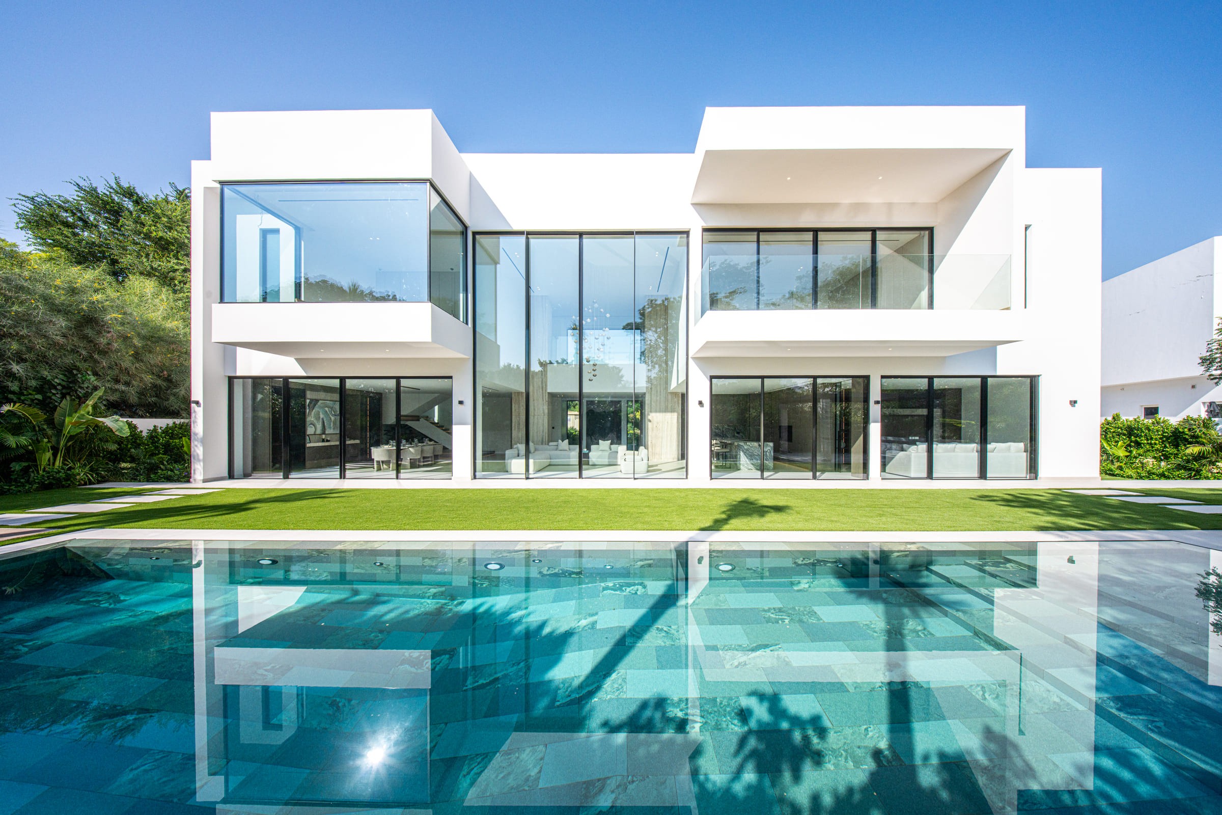 Image of a large villa with big glass windows and a pool 