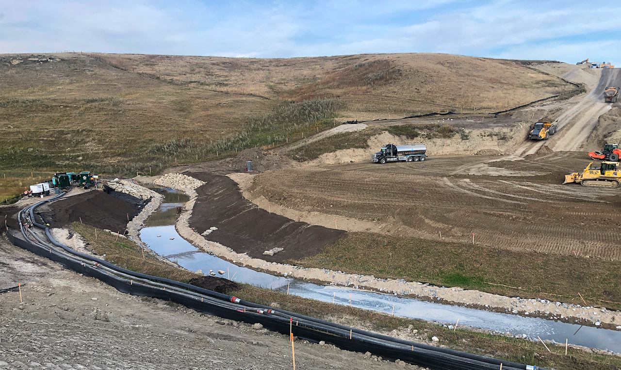 Equipment constructing realigned West Nose Creek channel with erosion control liner and prairie landscape