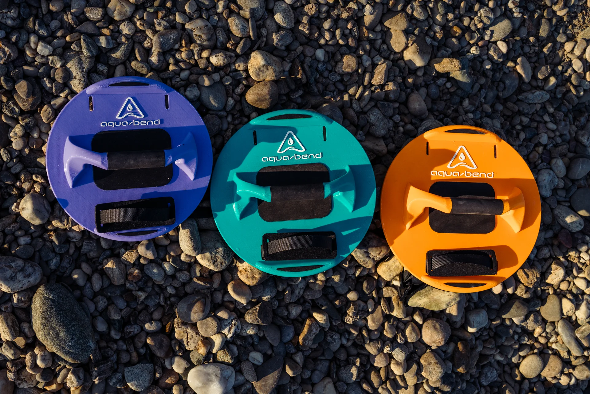 Aqua-Bend FLOW, FIT and FLEX discs in Grip Edition displayed side by side on beach rocks
