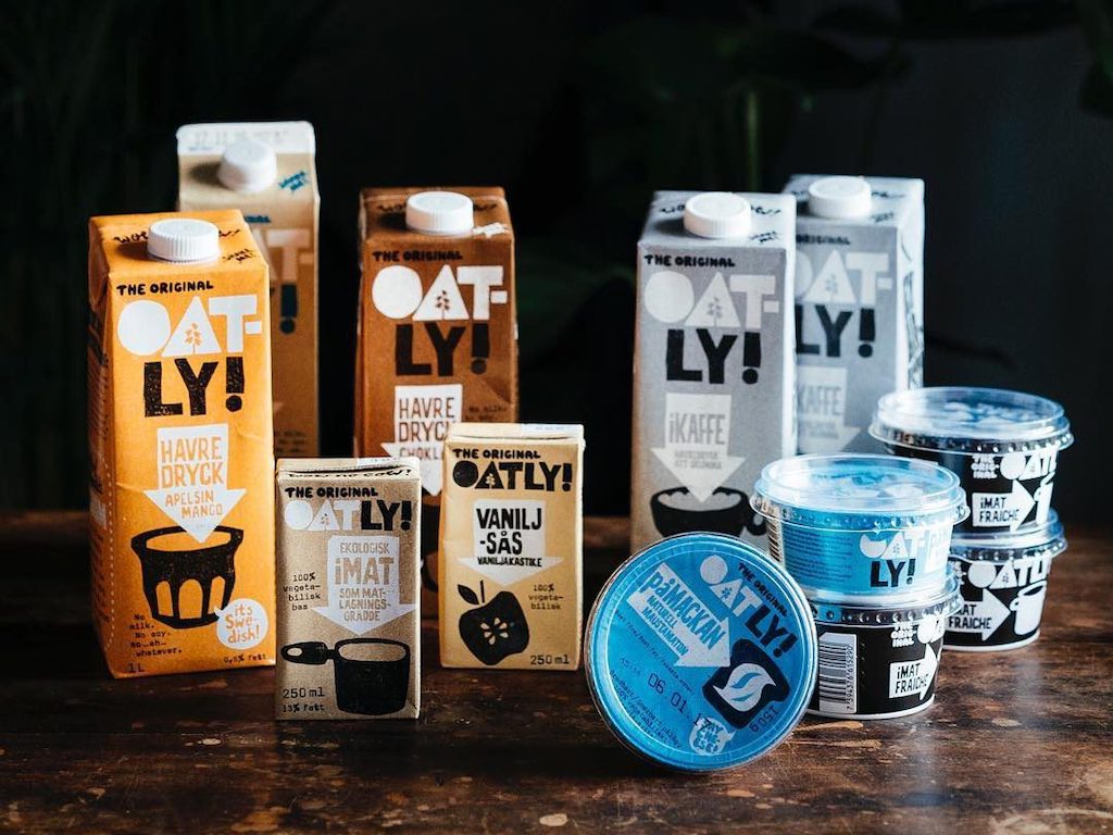 Assorted Oatly oat-based products, including milk cartons and yogurt cups, arranged on a table—featured in a blog about Oatly as an investment.