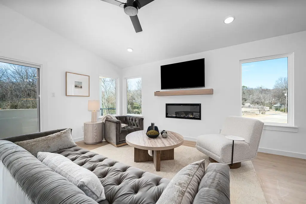 A white building with a balcony and windows, representing an apartment complex, set against a serene blue sky.