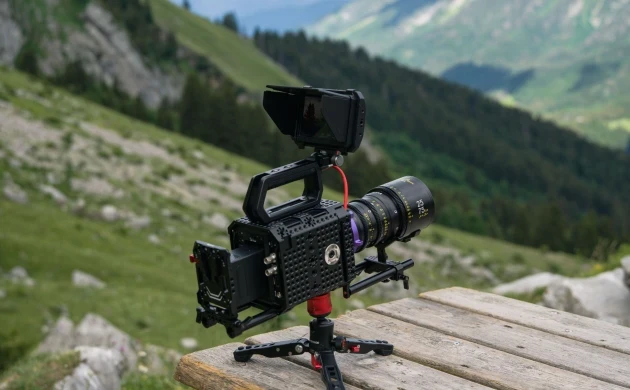 A cinema camera fitted with a DZOFILM Arles zoom lens on a tripod in an alpine landscape