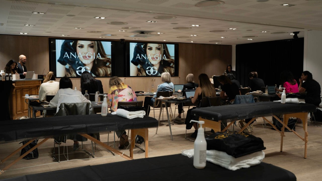 Formation Ana Gia : public attentif devant écrans projetant image mannequin, tables de massage préparées.