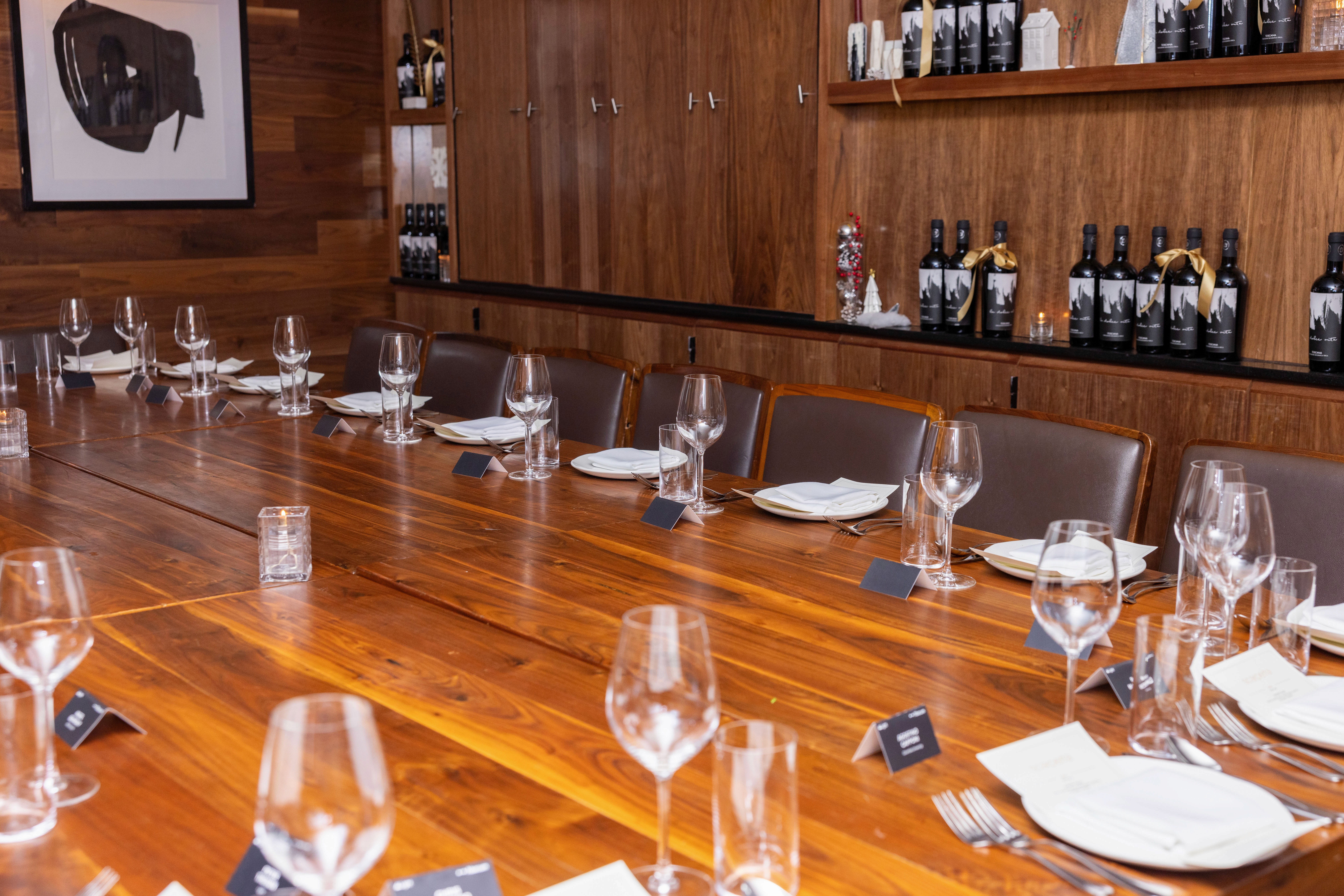 A large, wood conference table set for a meeting, with glasses and plates at each seat, in a formal room.