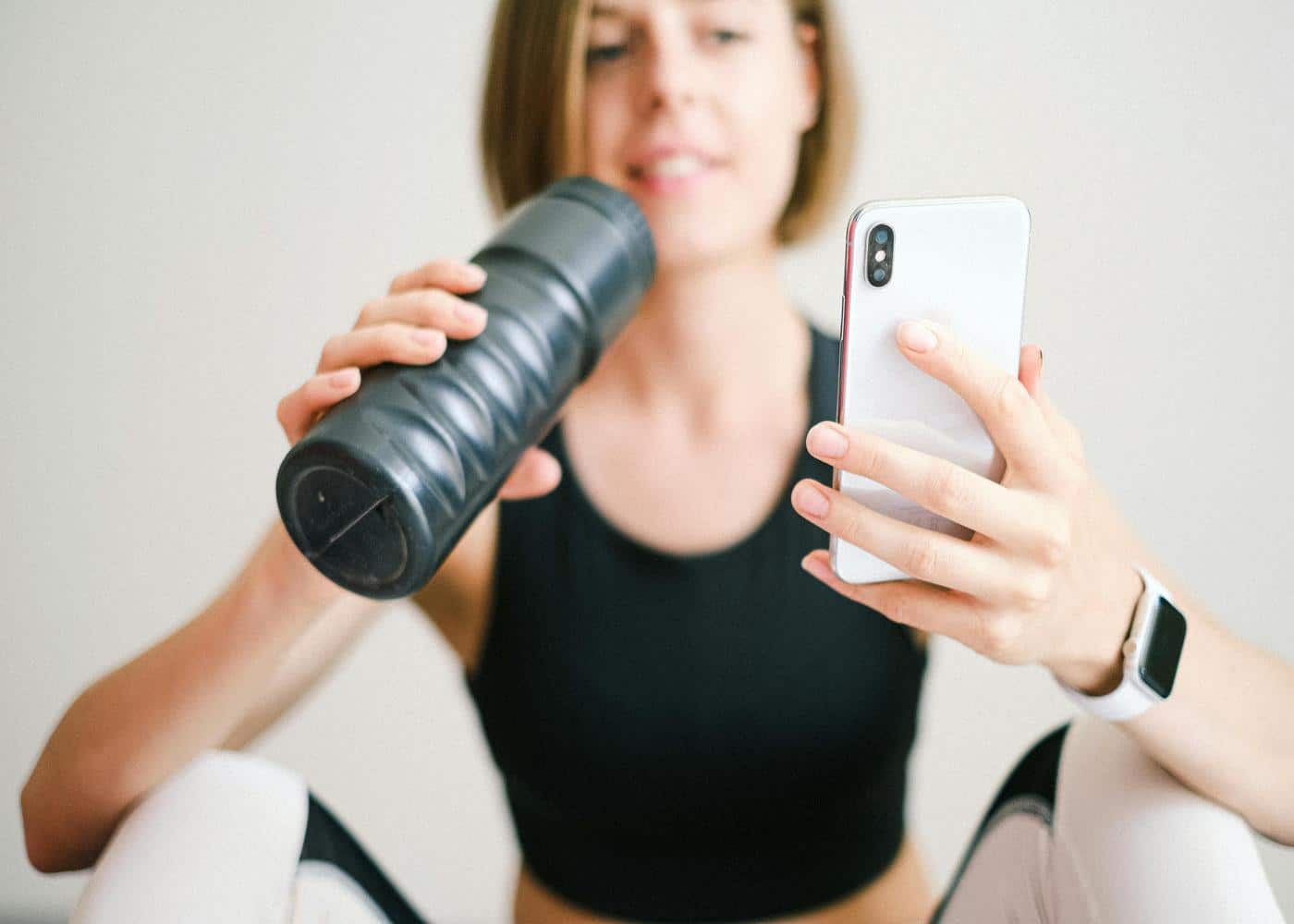 Smiling woman with water bottle looking at smart phone