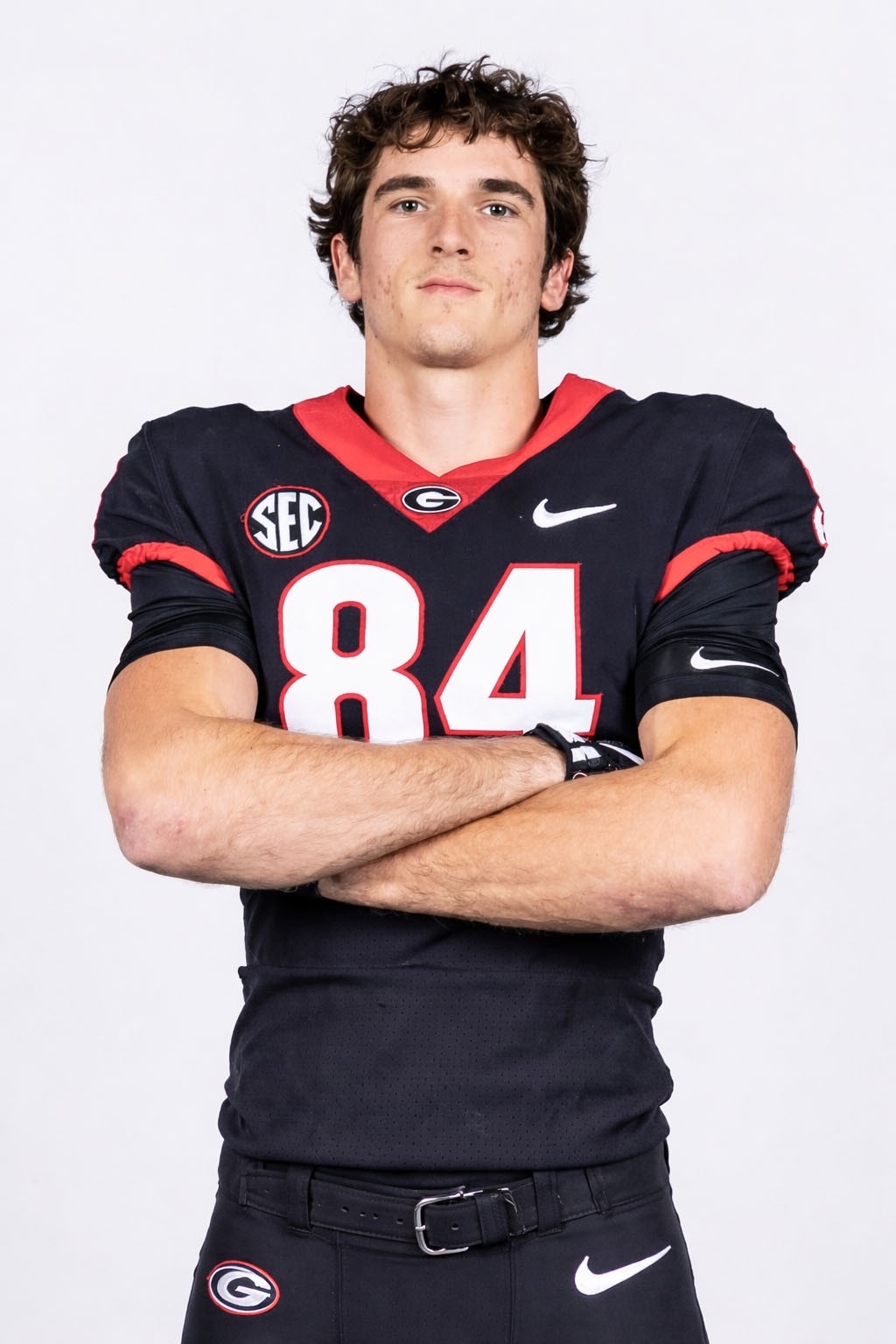 Dallas Dickerson wearing a black Georgia Bulldogs uniform with the number 84 stands with arms crossed in front of a plain white background.