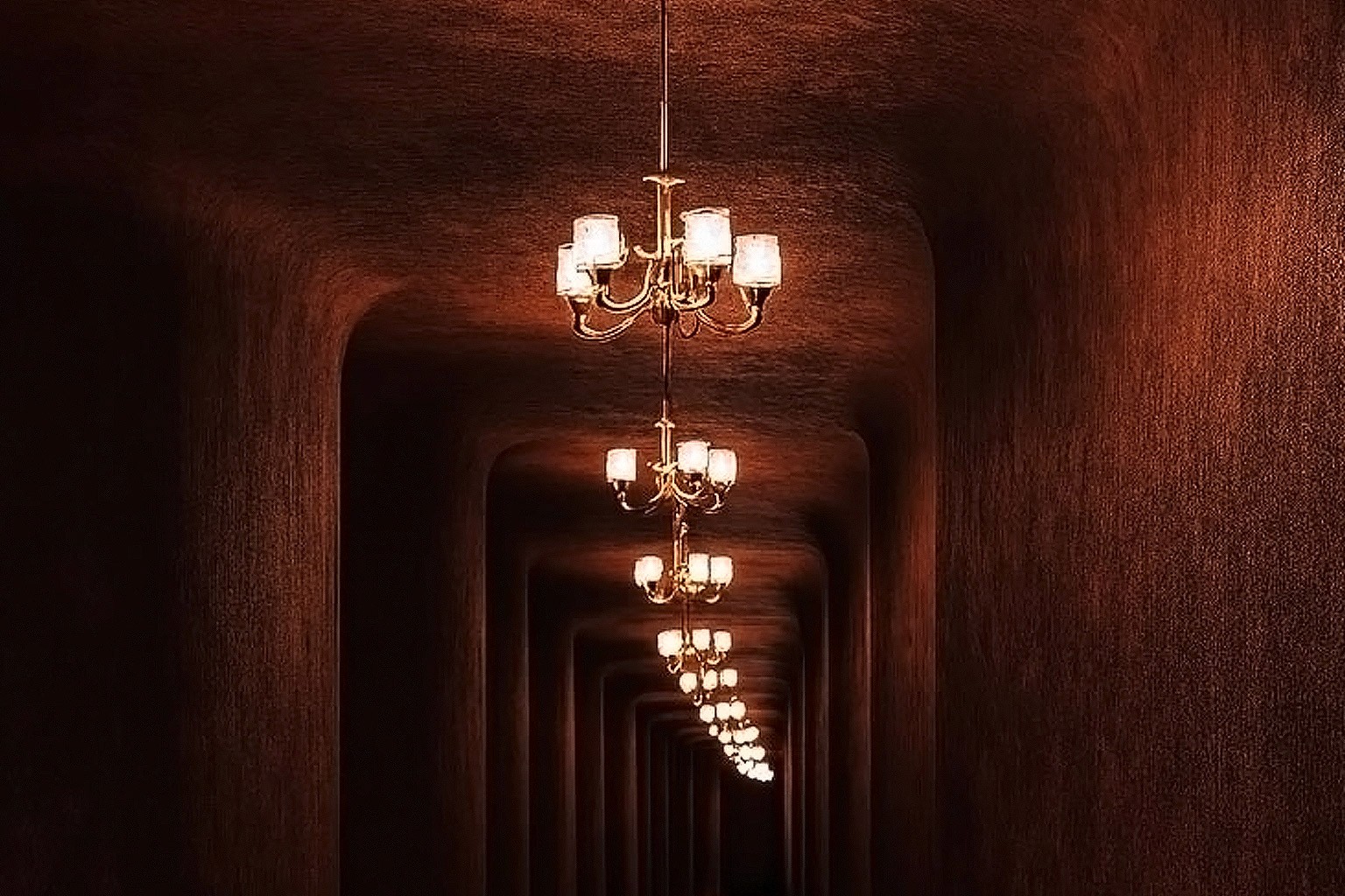 Dark brown corridor with curved walls, floor lighting, and elegant chandeliers.