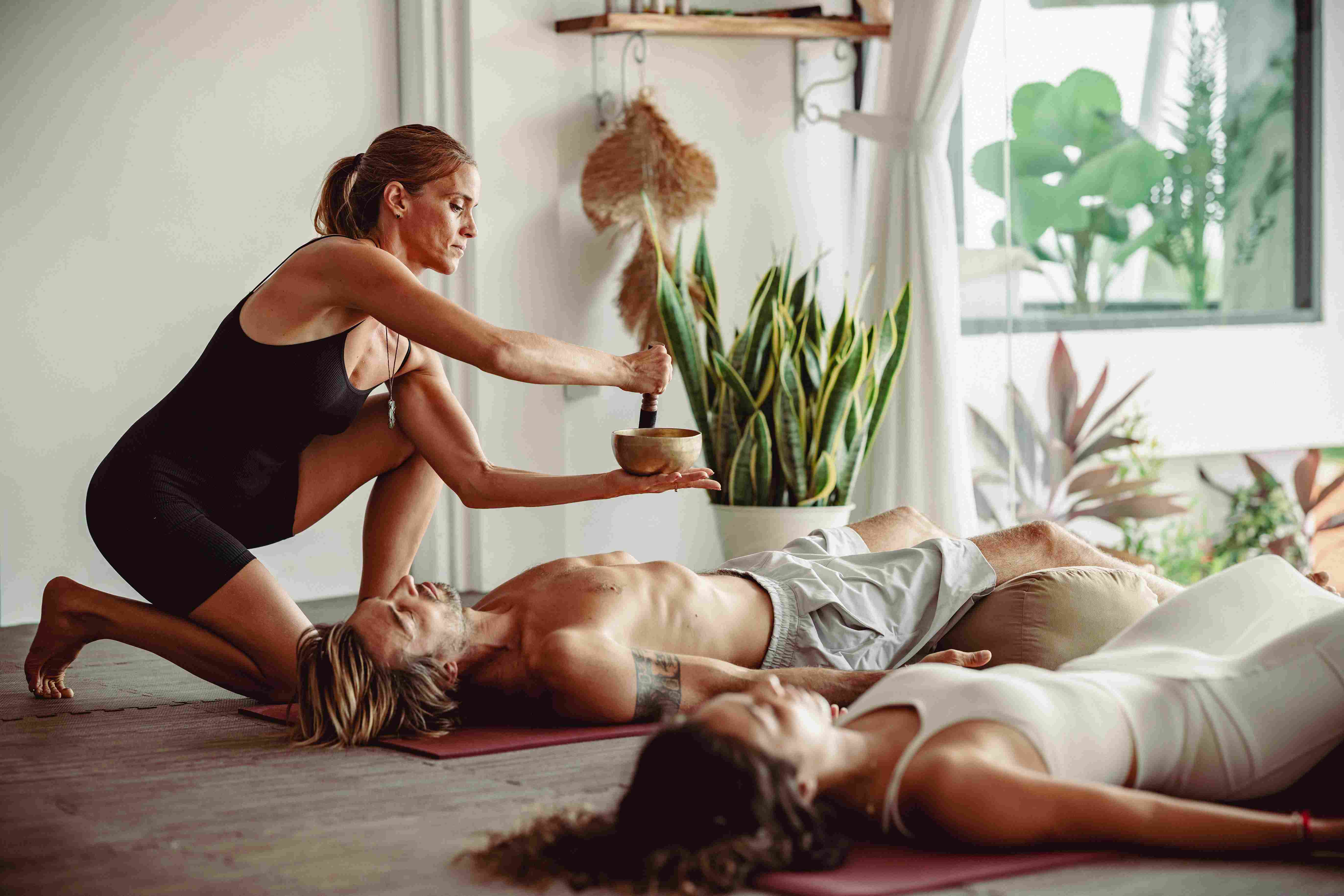 Sound healing therapy session with Tibetan singing bowl placed on student's chest during relaxation class.