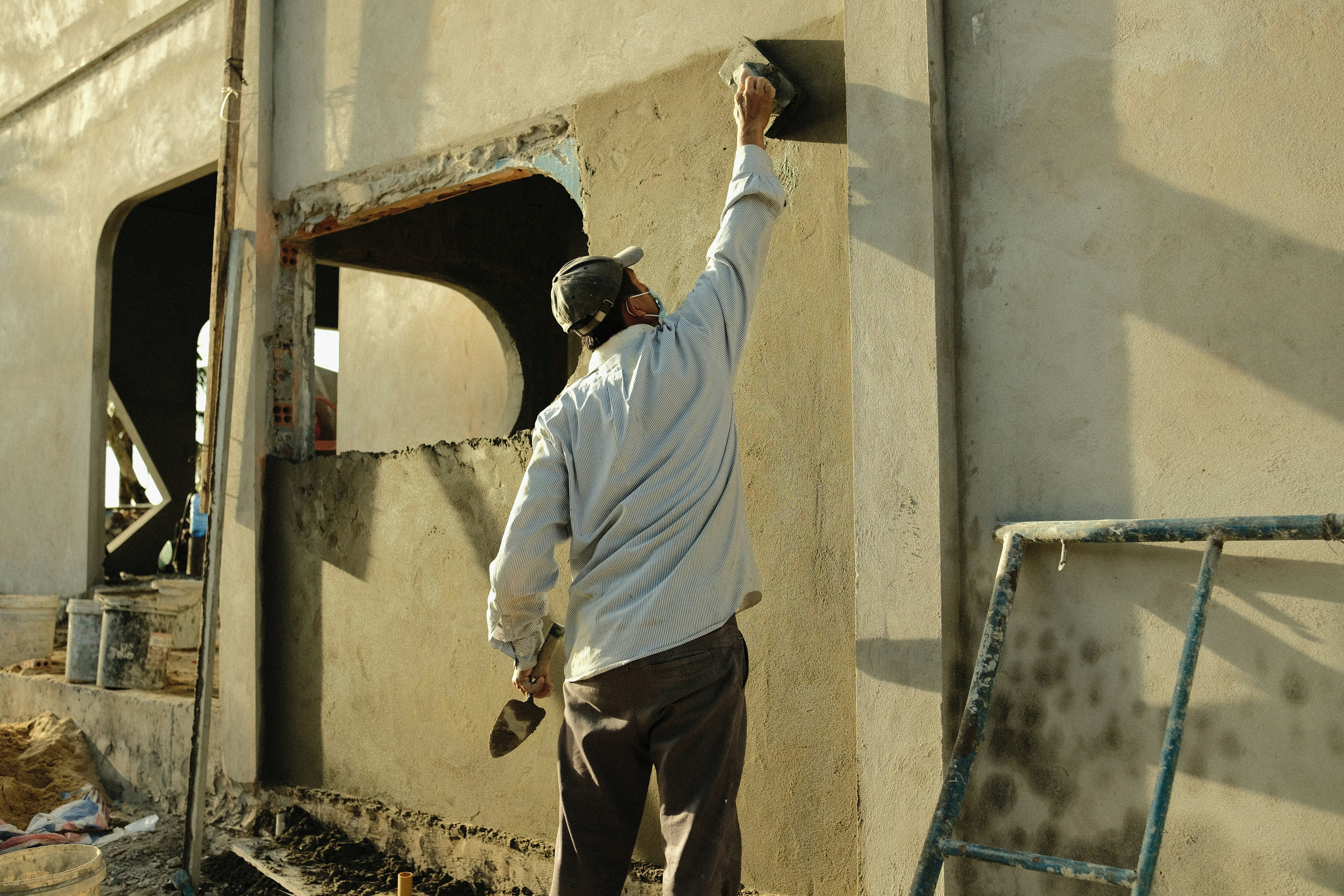 a man standing next to a building with a hammer