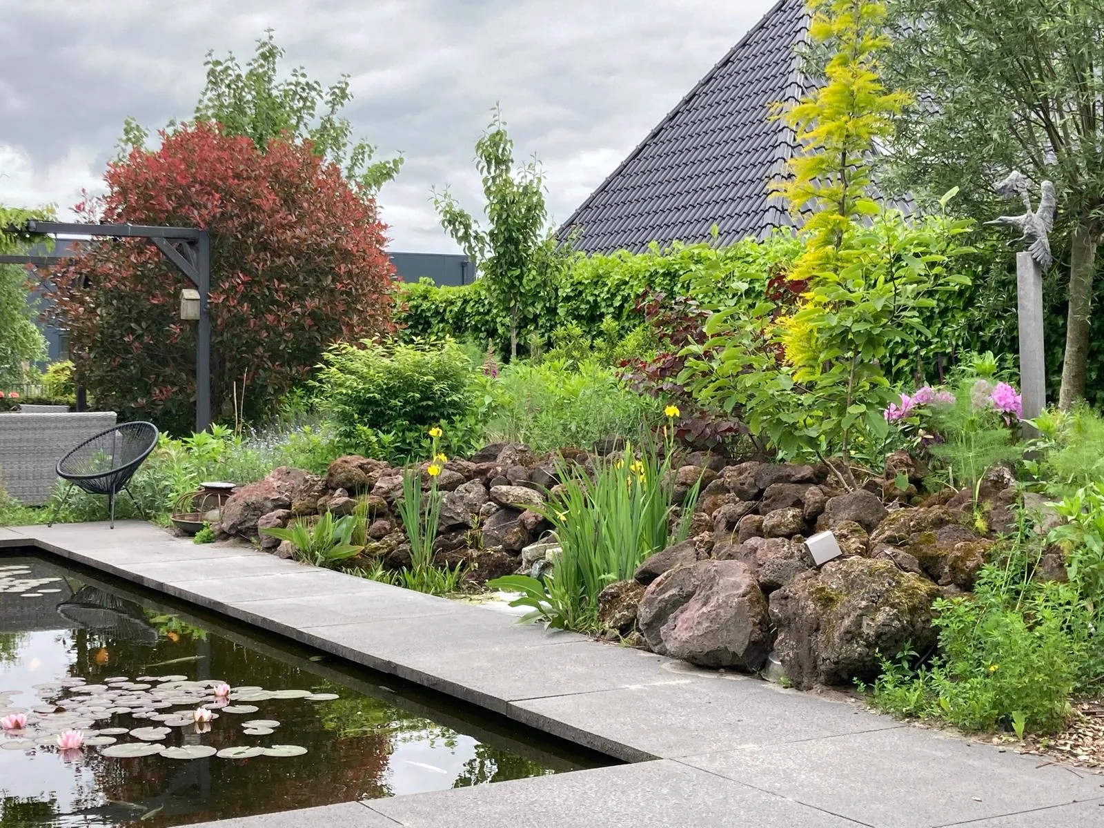 Tuin met vijver, houten vlonderterras en beplanting in moderne siertuin — tuinaanleg in Gorredijk / Friesland