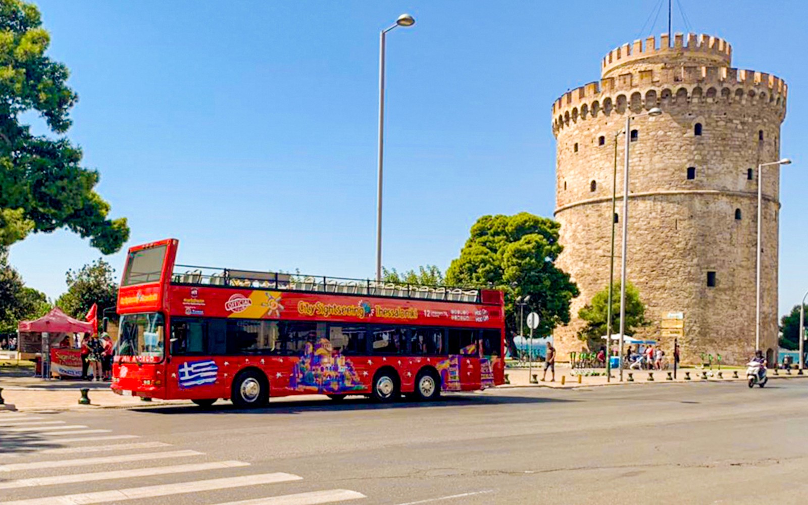 Piros emeletes busz a Fehér Torony mellett a Thessaloniki Hop-On-Hop-Off túrán.