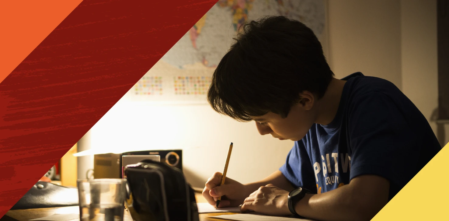 Little boy writing under dim lamp light