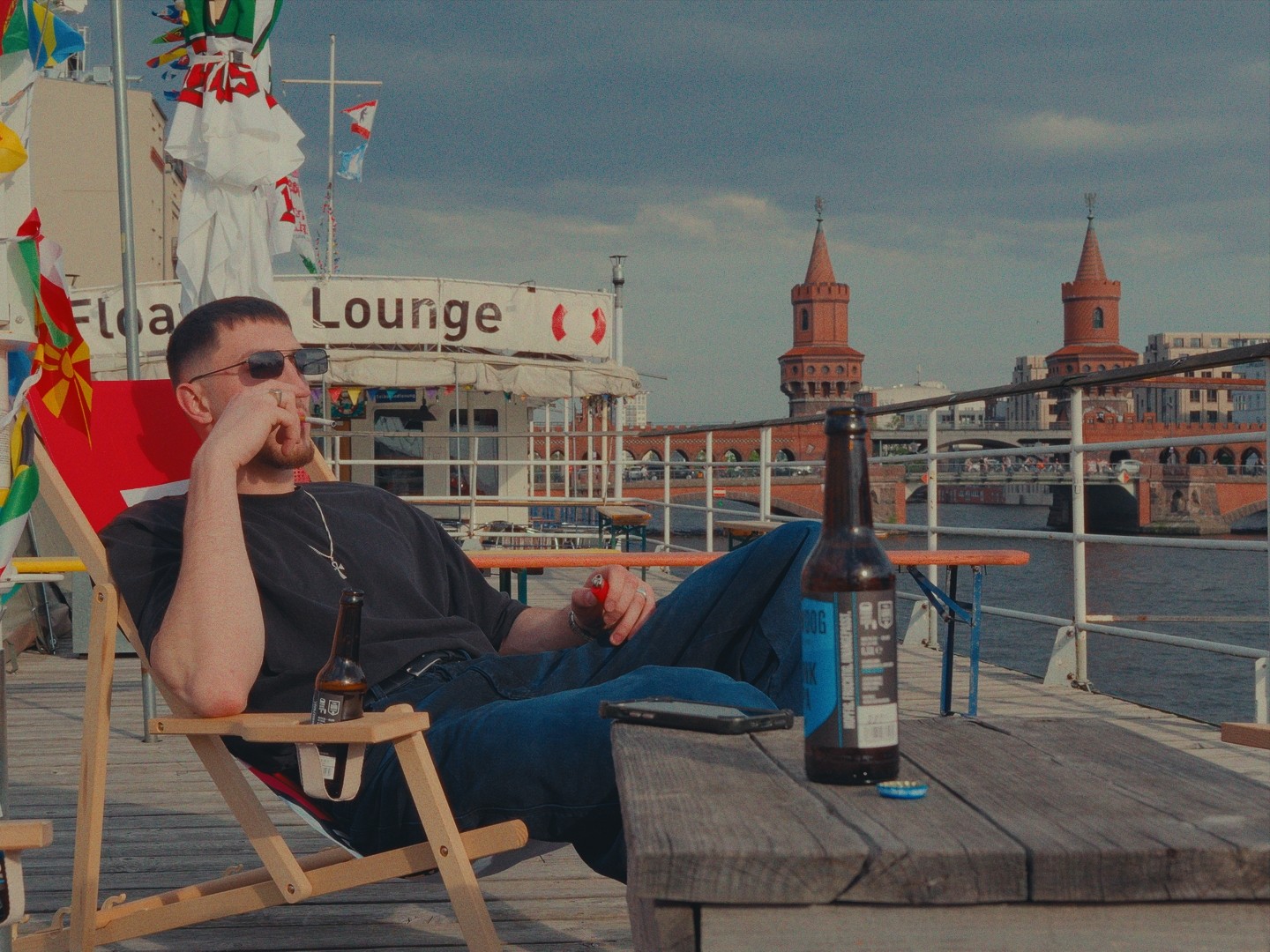 Personne assise sur une chaise longue, profitant du soleil près d'une terrasse flottante à Berlin.