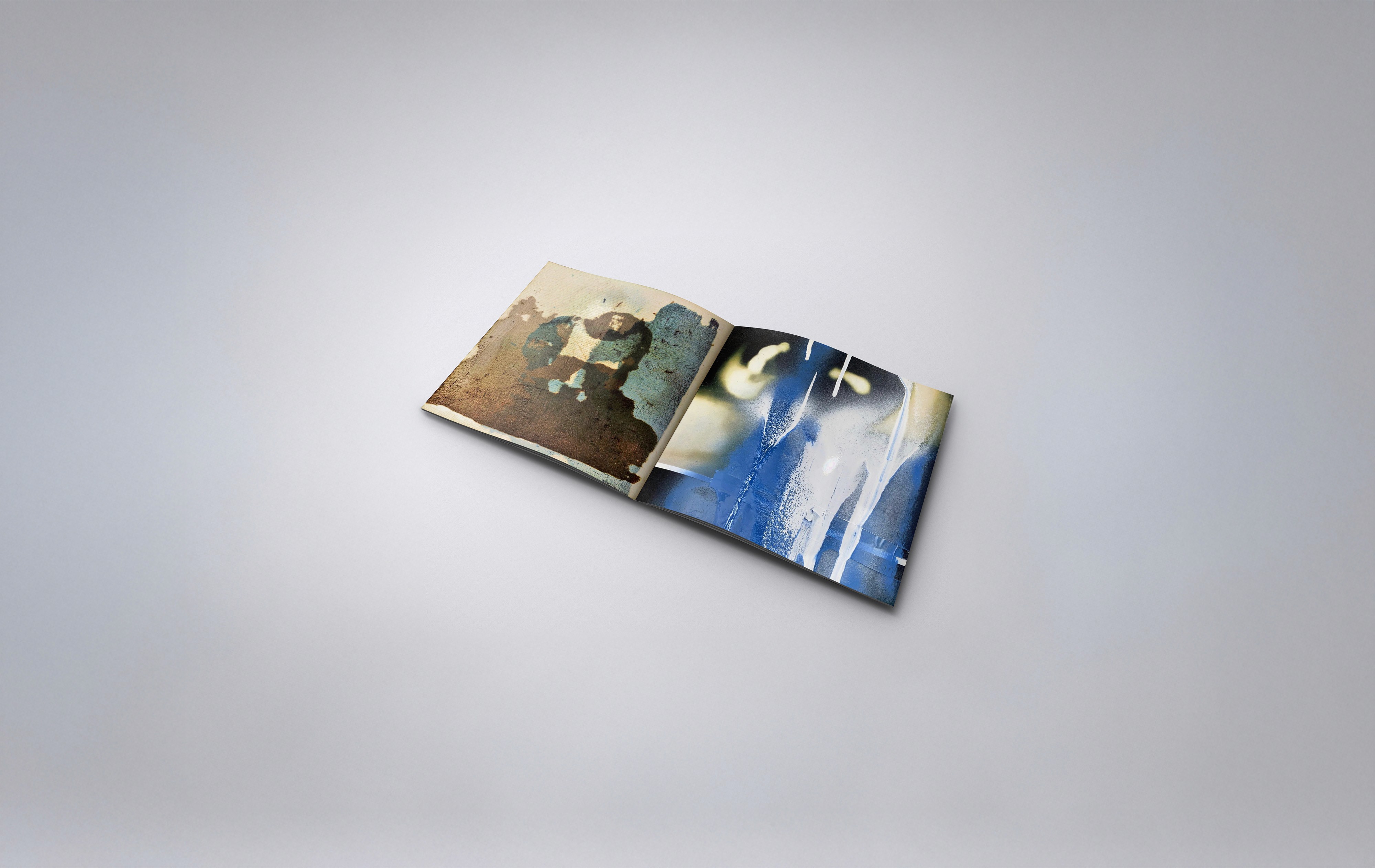 An open art book featuring abstract spreads. The left page shows a sepia-toned, weathered composition resembling silhouettes or faded figures. The right page contrasts with cool blue and white tones, suggesting fluidity, dripping textures, and dreamlike motion. The image evokes memory, time, and emotional resonance.