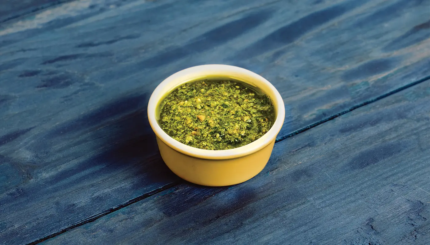 Garlic Mojo in a small yellow dish on blue wooden boards.