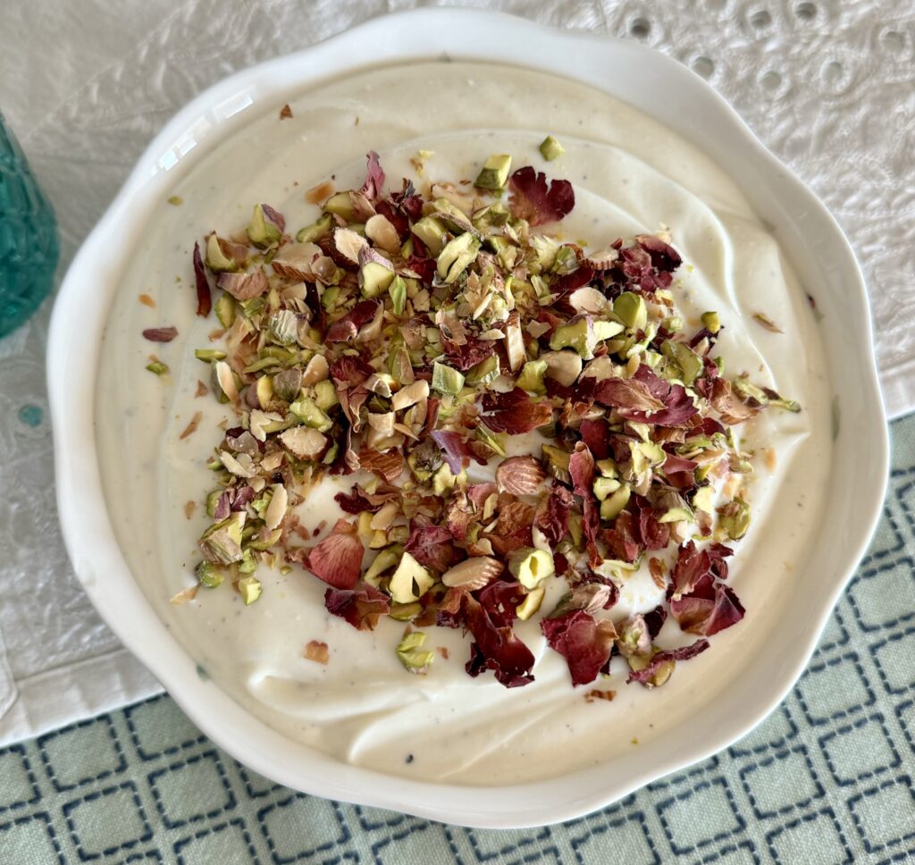 Shrikhand served in a bowl garnished with nuts and rose petals.