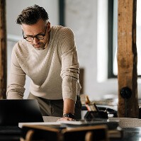 A middle-aged man standing over a laptop as he works