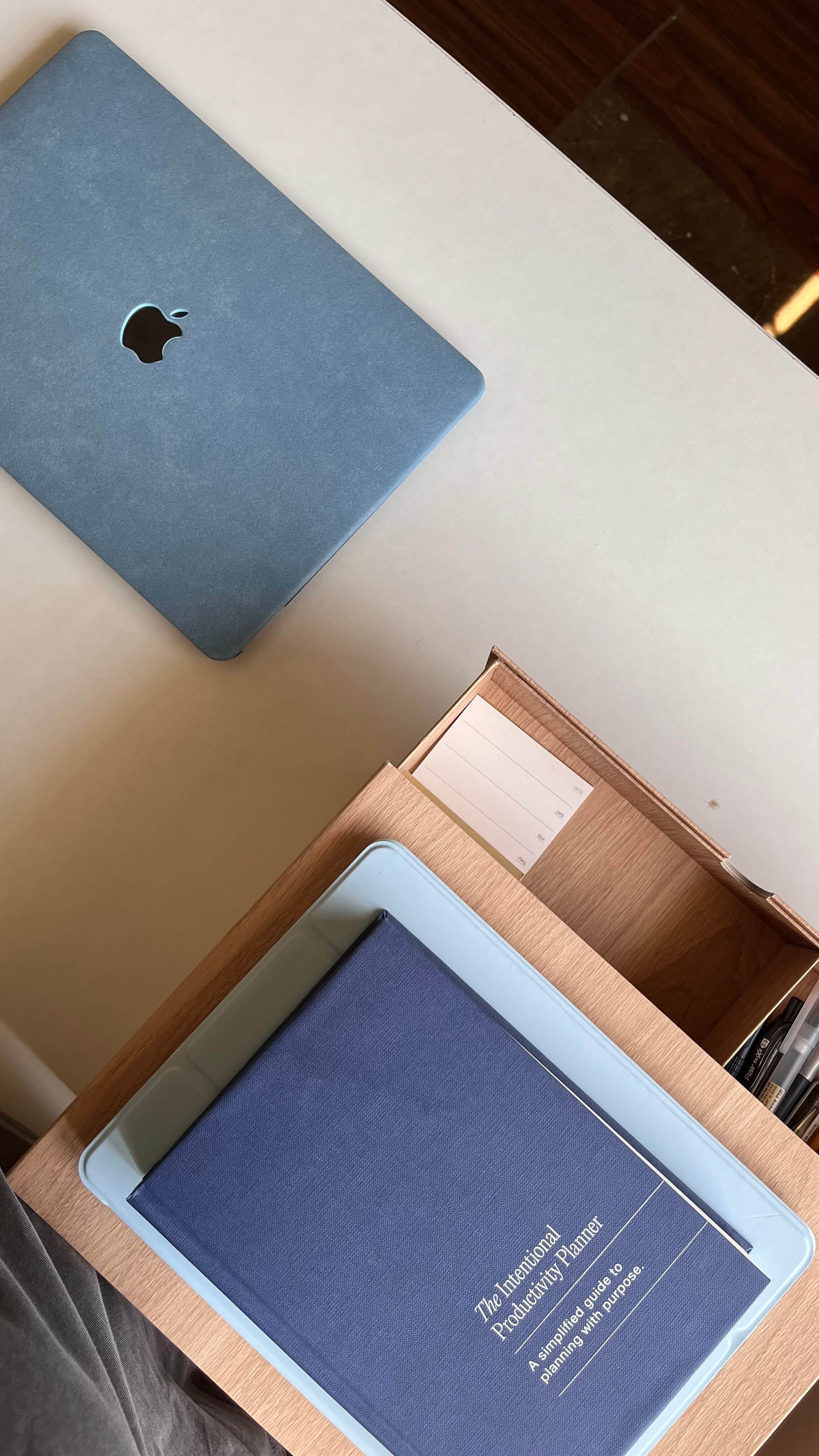 a desk shot from above with a stack of books and a laptop sitting on it