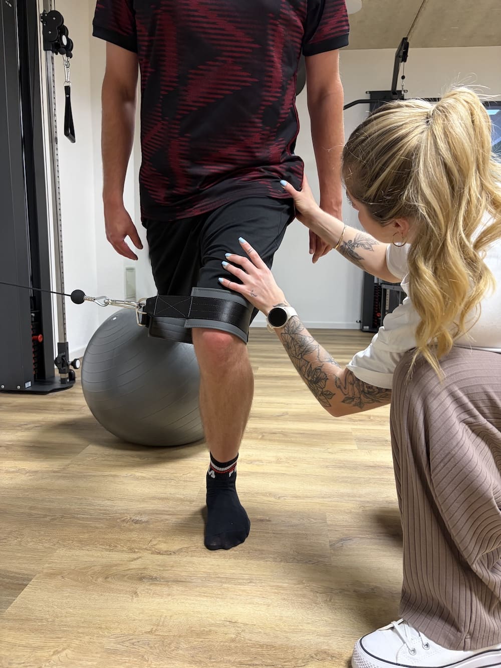 Medizinische Trainingstherapie in Rheinbach, Übung am Kabelzug mit Korrektur durch Physiotherapeutin Lorena Gullotta