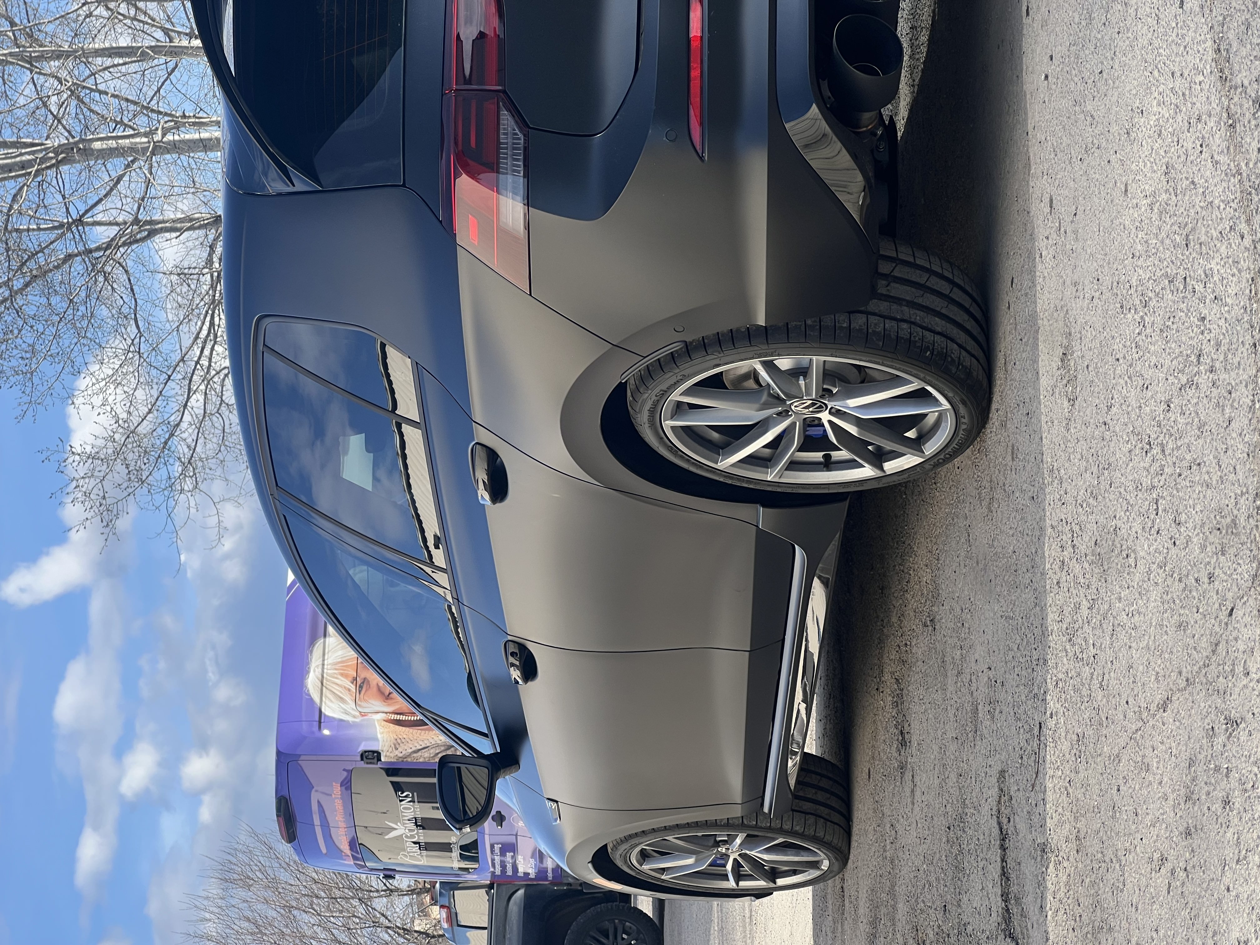 Satin dark grey wrapped Volkswagen Golf R with silver wheels, shown from rear angle outdoors.