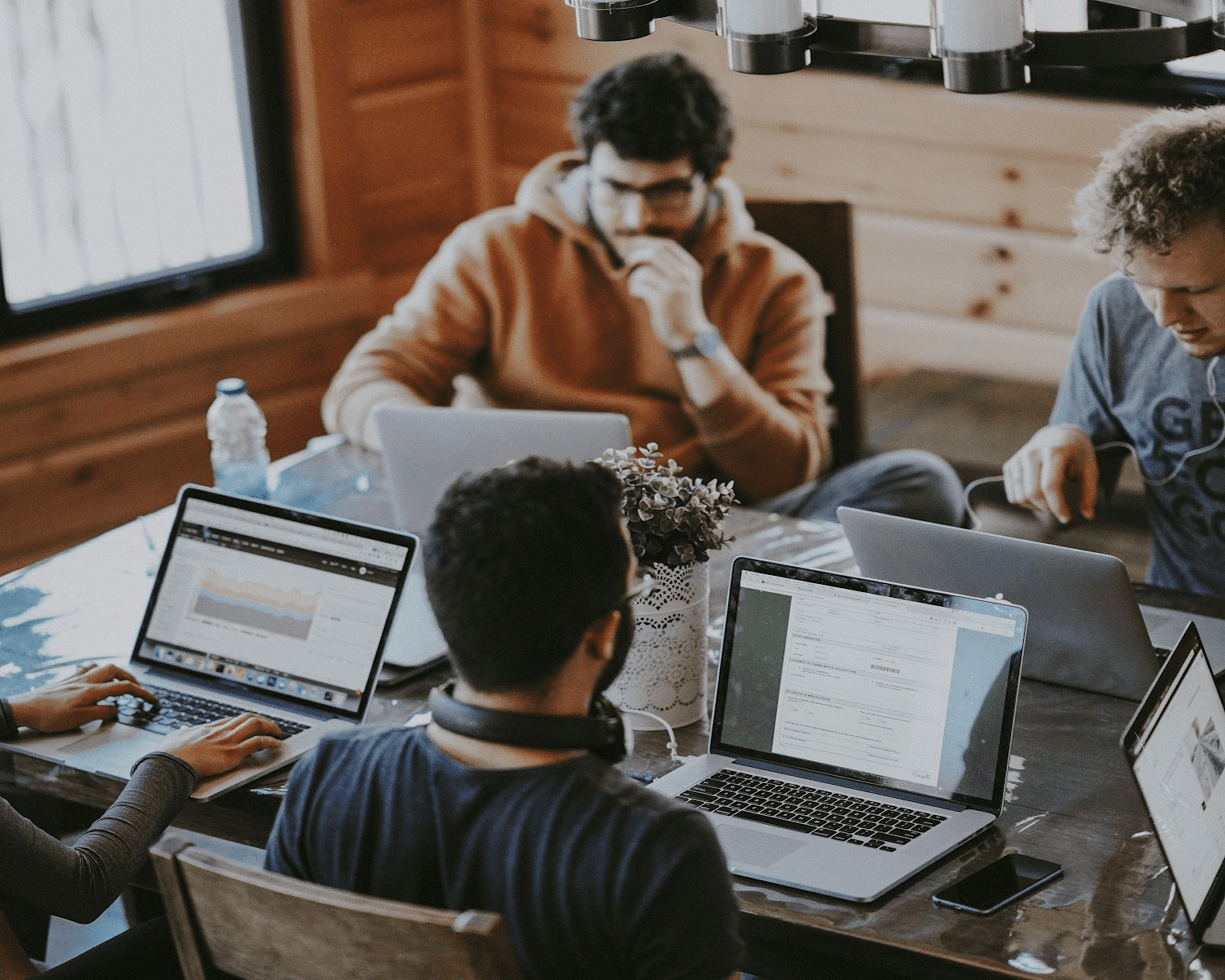 Group of four people working on laptops around wooden table