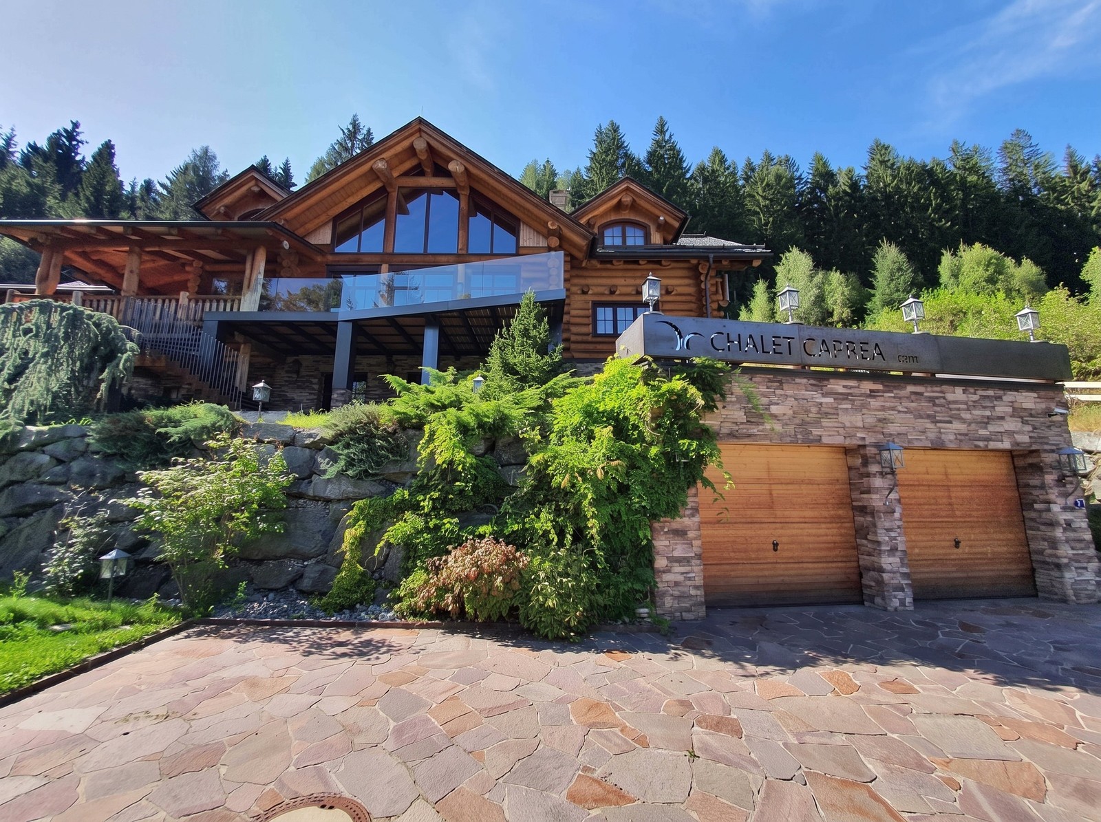 The chalet in summer from the drive, garage doors in the stone wall below
