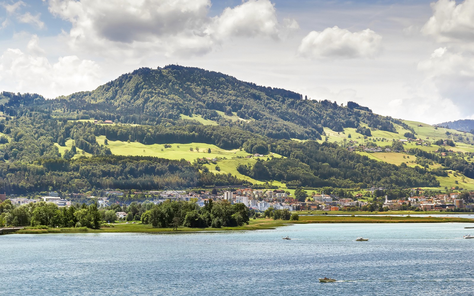 苏黎世市景，背景是苏黎世湖上的船只和郁郁葱葱的丘陵。