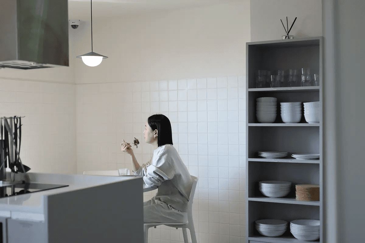 A woman with her hair tied back smiles while reading an open book in the library at Mangrove Sinchon.