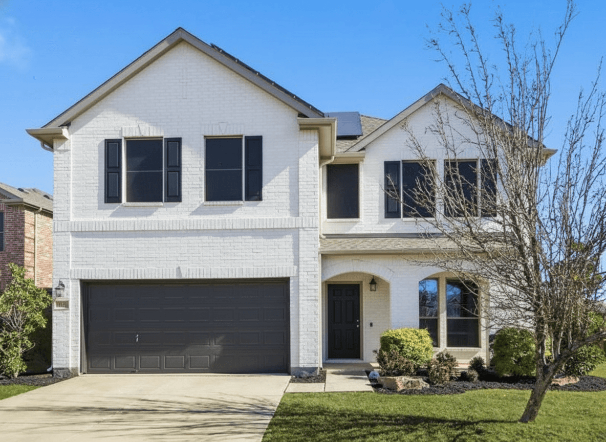 Same brick house painted bright white with dark charcoal garage door and black shutters
