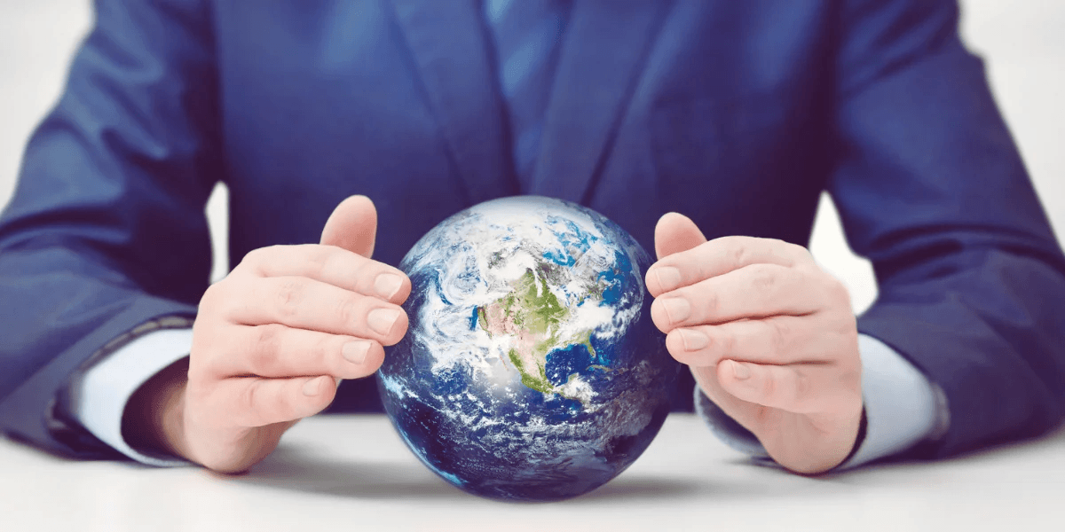 A person in a suit holds a globe, symbolizing care and responsibility for the Earth.