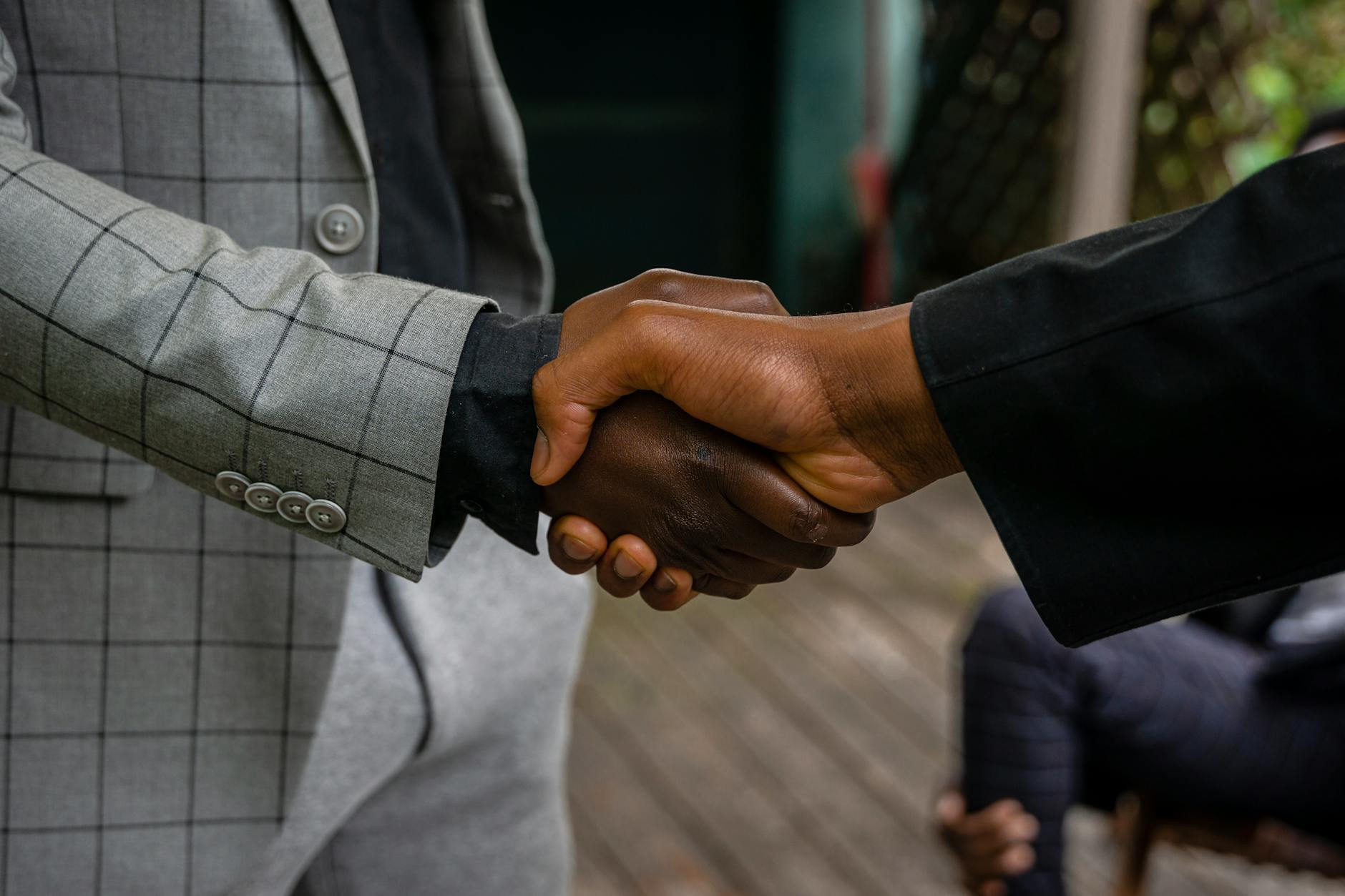 A teacher and a local construction foreman shaking hands in front of a blueprint at a job site visit.