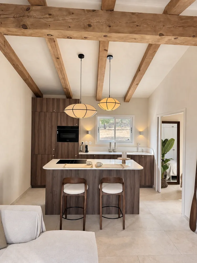 Cuisine avec façades bois, îlot et poutres apparentes