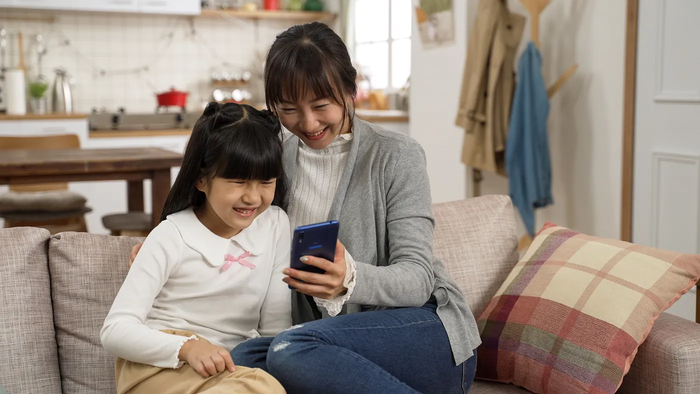 A mother and daughter looking at a mobile phone together