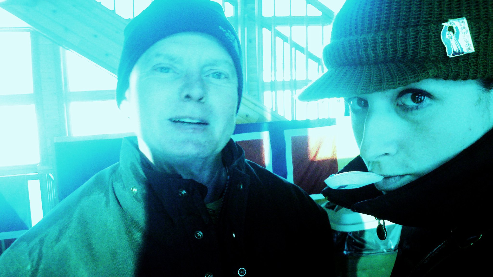 Two individuals in winter hats and jackets, captured in a blue-tinted environment.