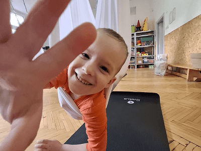 Usměvavý chlapec mávající do kamery při cvičení na podložce