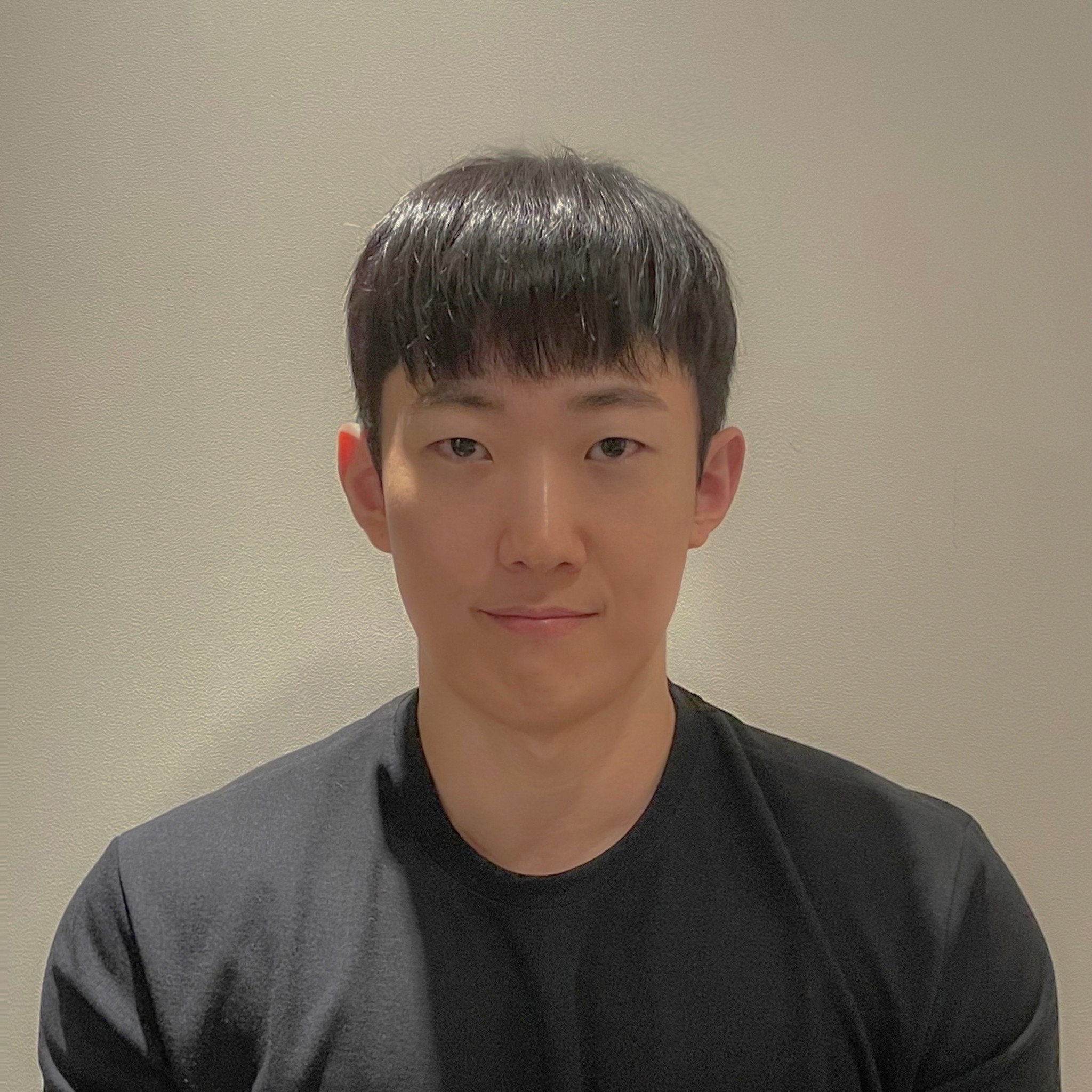 headshot of man with black hair and black shirt looking at the camera