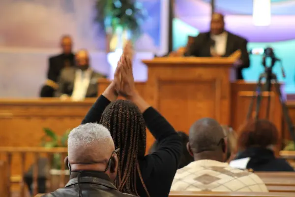 Congregation raising hands in worship during a church service at Peace Apostolic Church