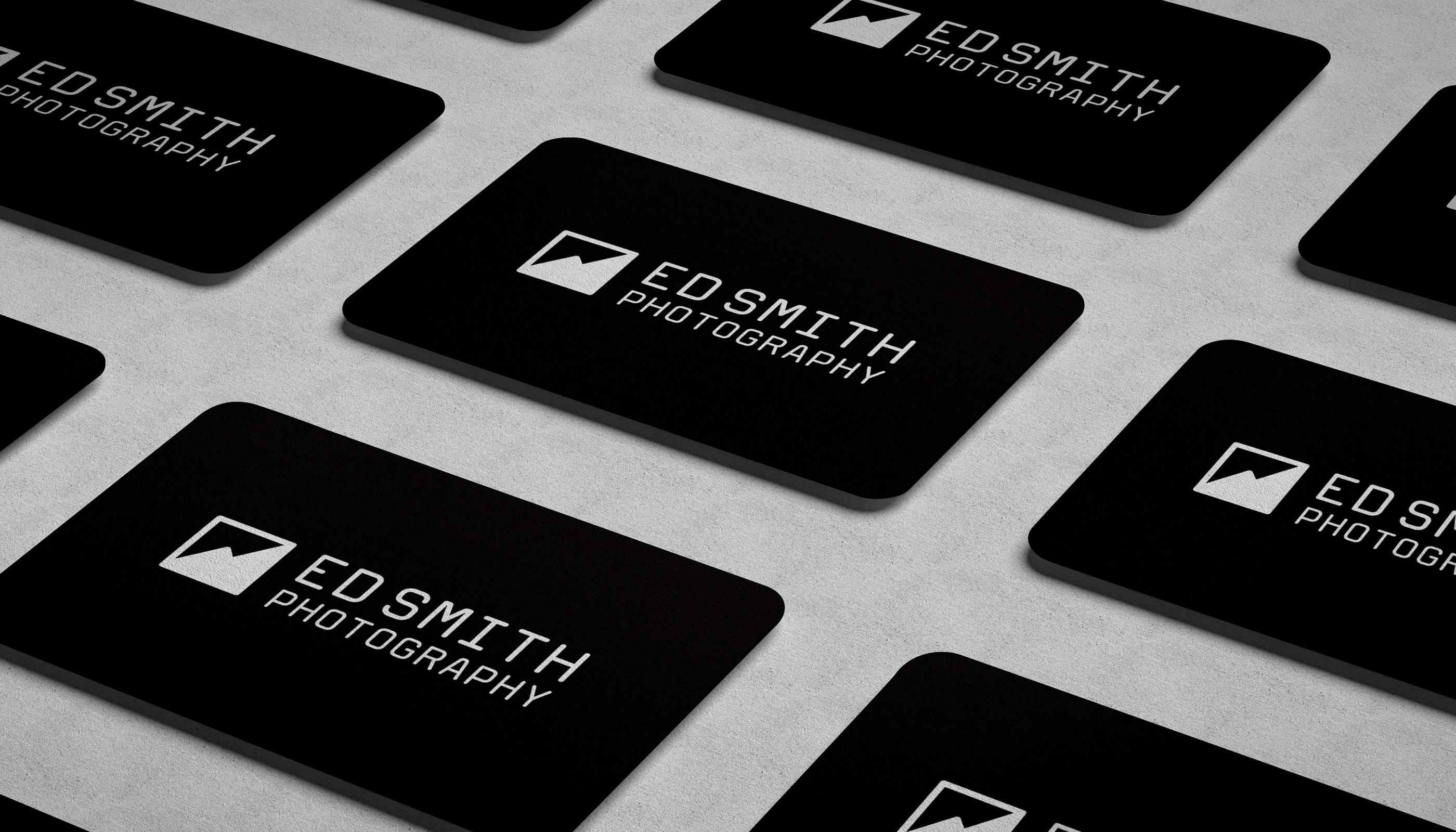 A group of Ed Smith business cards, black with white logo, in a grid on a surface.