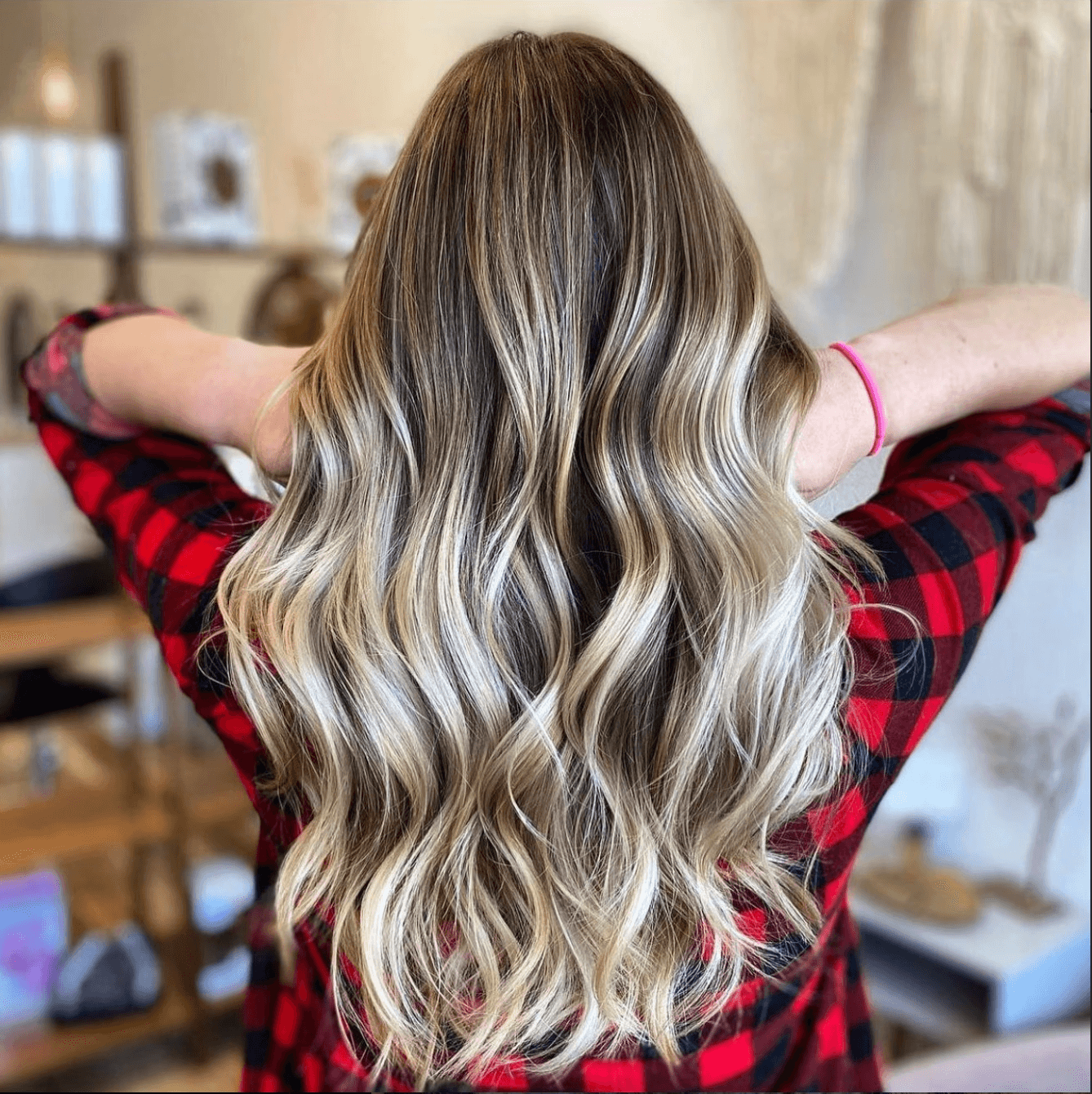 Back view of long, cool-toned blonde hair with seamless extensions, soft root shadow, and icy balayage, styled in defined beachy waves.