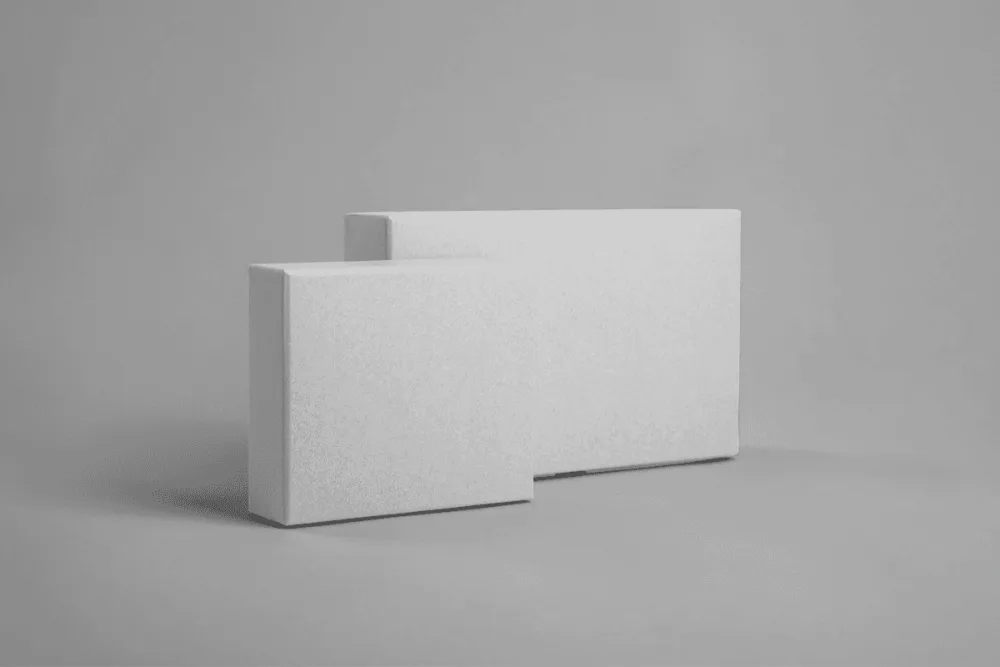 Set of two kraft paper boxes mockup with printed logos, one in blue and the other in white. The boxes are placed against a neutral gray background, ideal for branding presentations.
