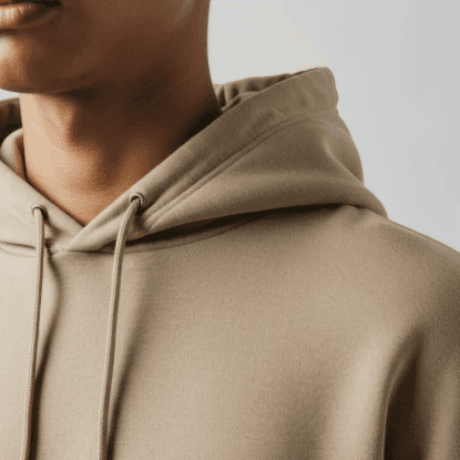 Close-up of a person wearing a beige hoodie. The focus is on the hoodie’s texture and drawstrings. The lighting is soft, creating a calm tone.