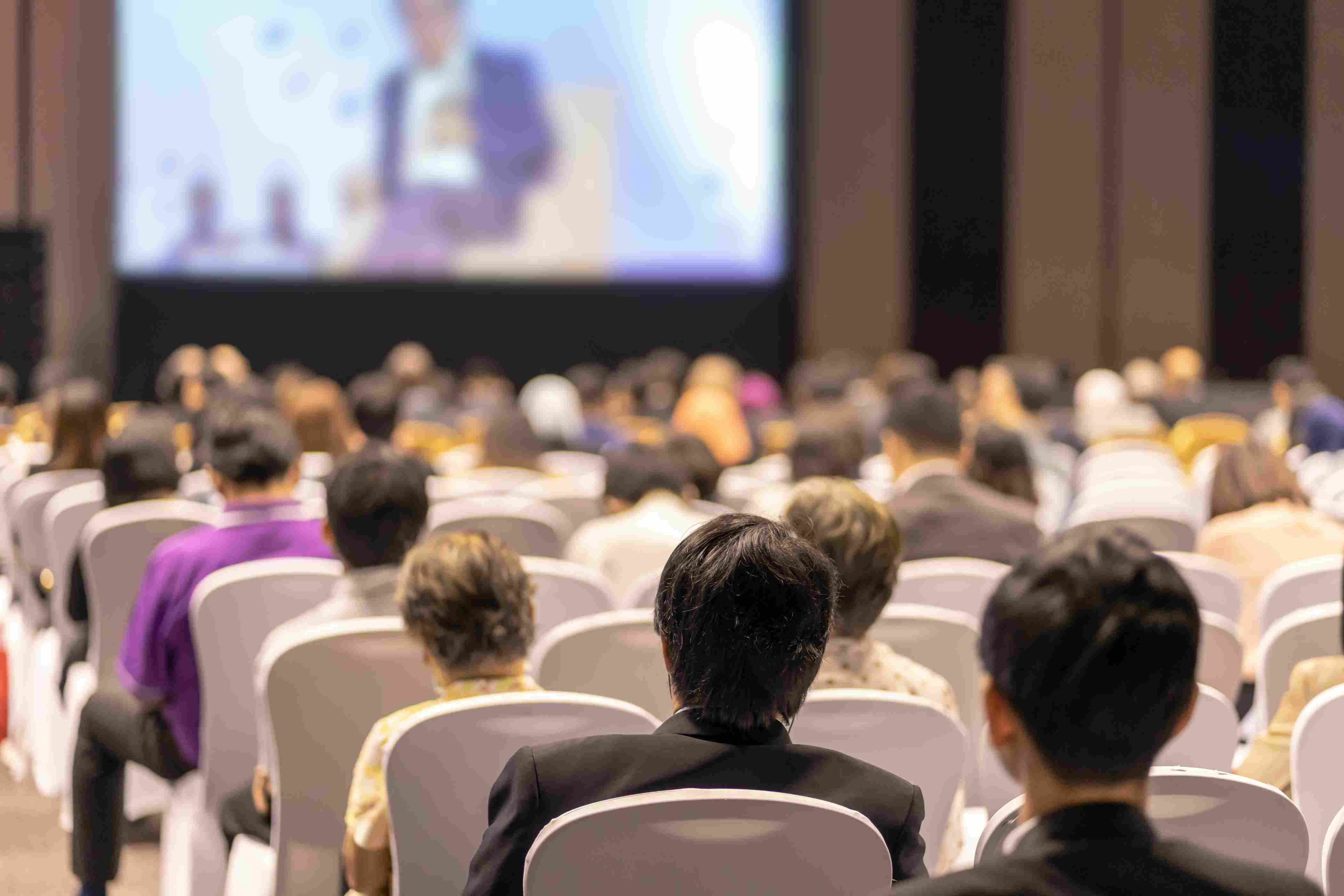 Engaged audience attending a live event webcast with a keynote speaker on stage