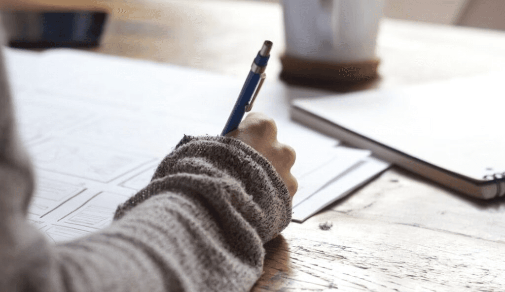 High school student writing a music theory research paper with sheet music and academic notes on a desk