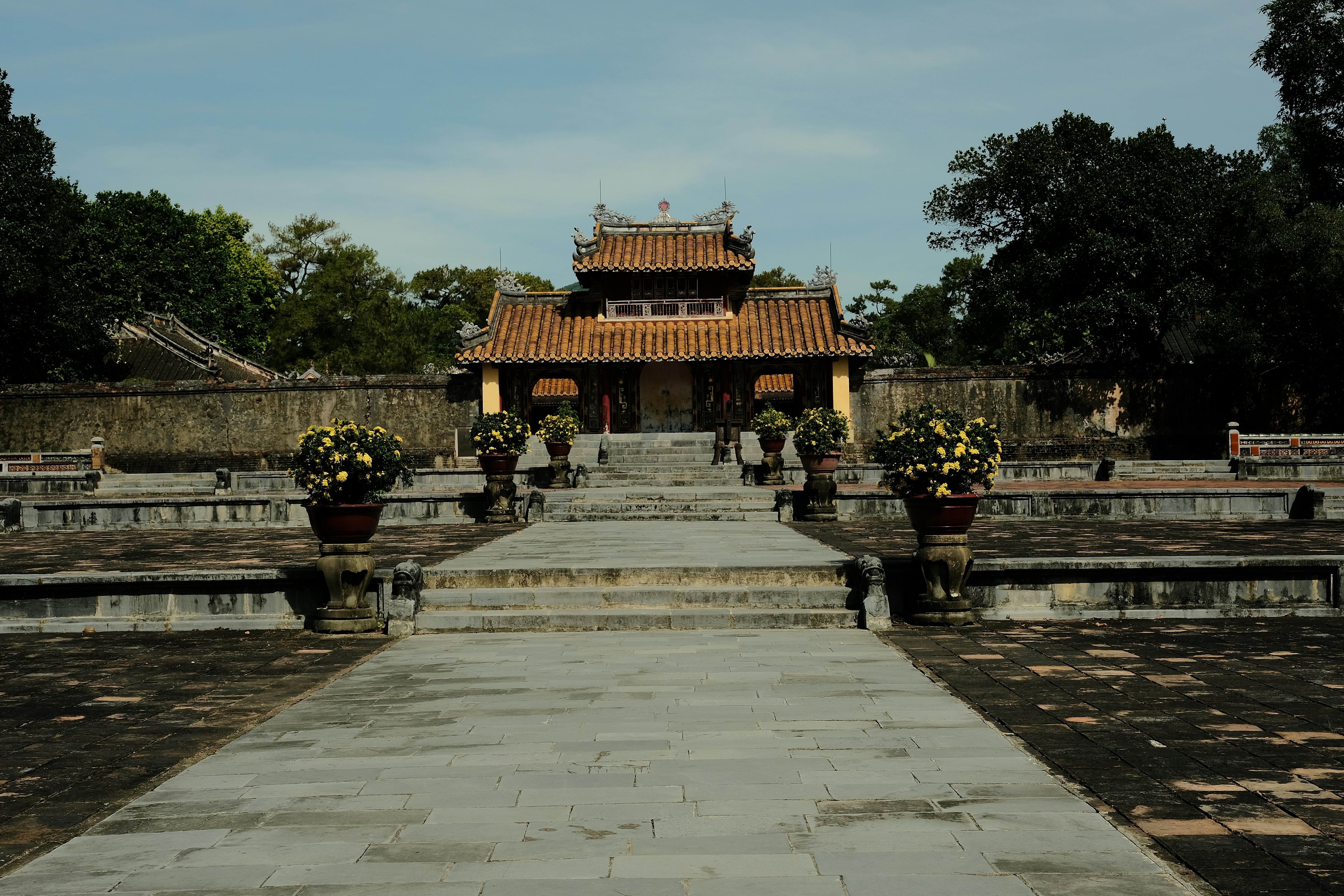 a stone walkway leading to a building with a pagoda in the background